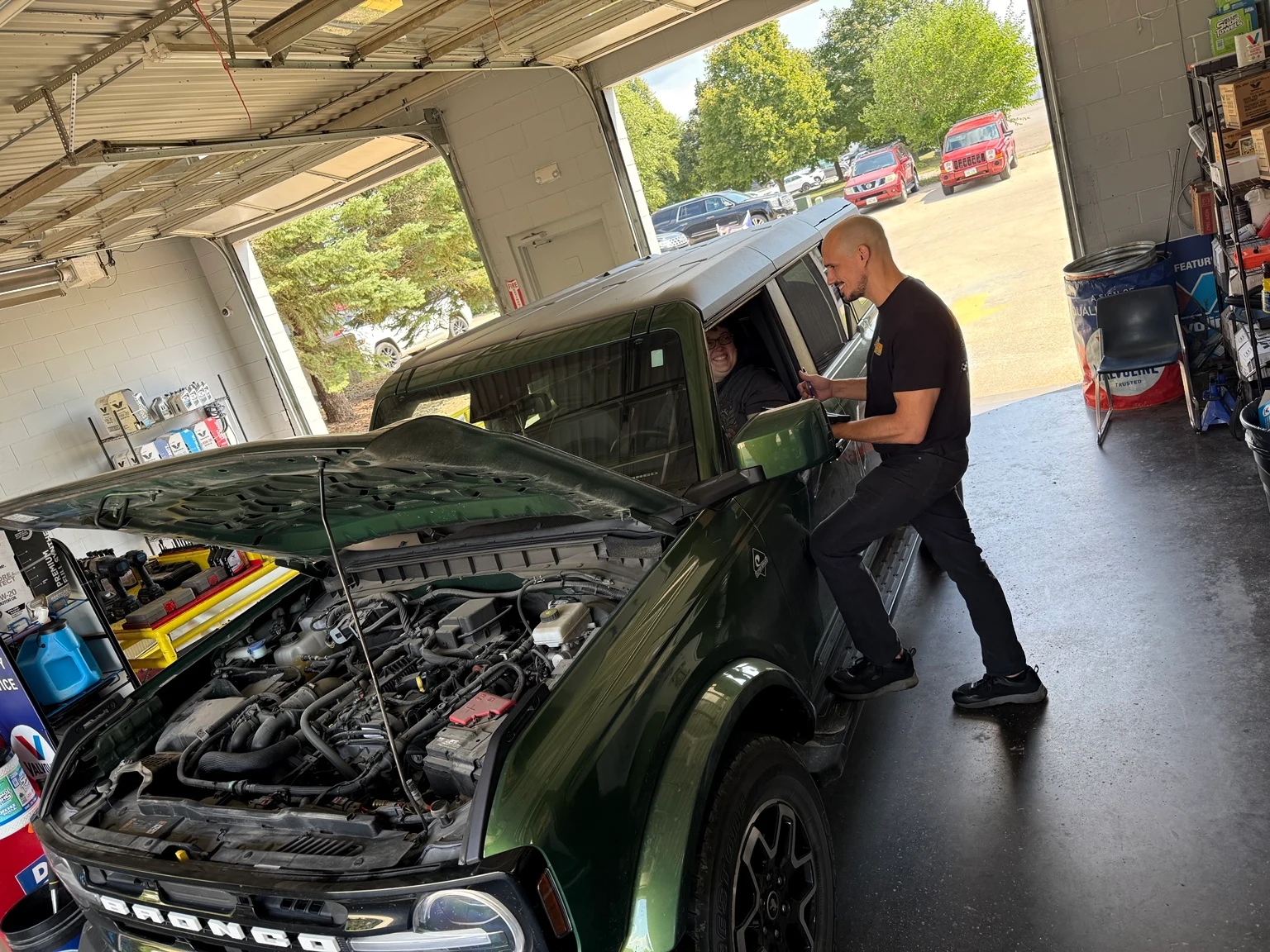 A Roberts employee smiling with a customer beside their vehicle in the service bay