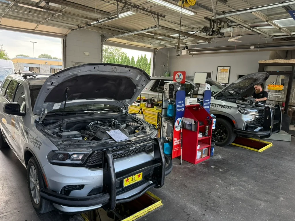 Two Iowa State Patrol vehicles with their hoods open in Roberts Quick Lube service bays
